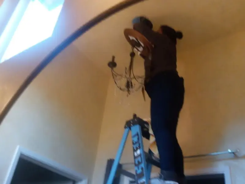 Electrician installing a chandelier in a Osprey residence